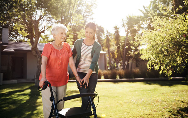 young woman helping elderly woman with walker