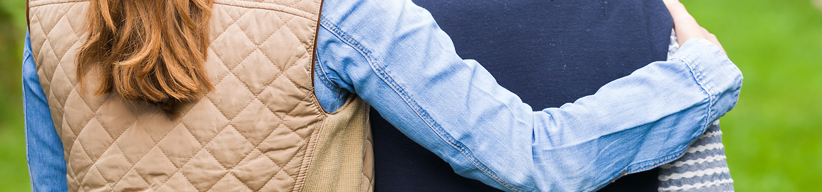 young woman's arm wrapped around elder woman's shoulder